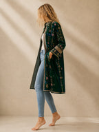 The House of Saffron long indigo velvet suzani jacket with intricate floral embroidery and side pockets on a model.