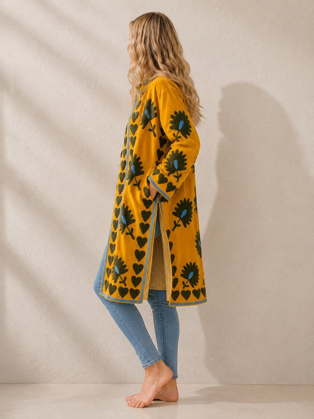 The House of Saffron long saffron velvet suzani jacket with floral embroidery and heart border, side view on model.
