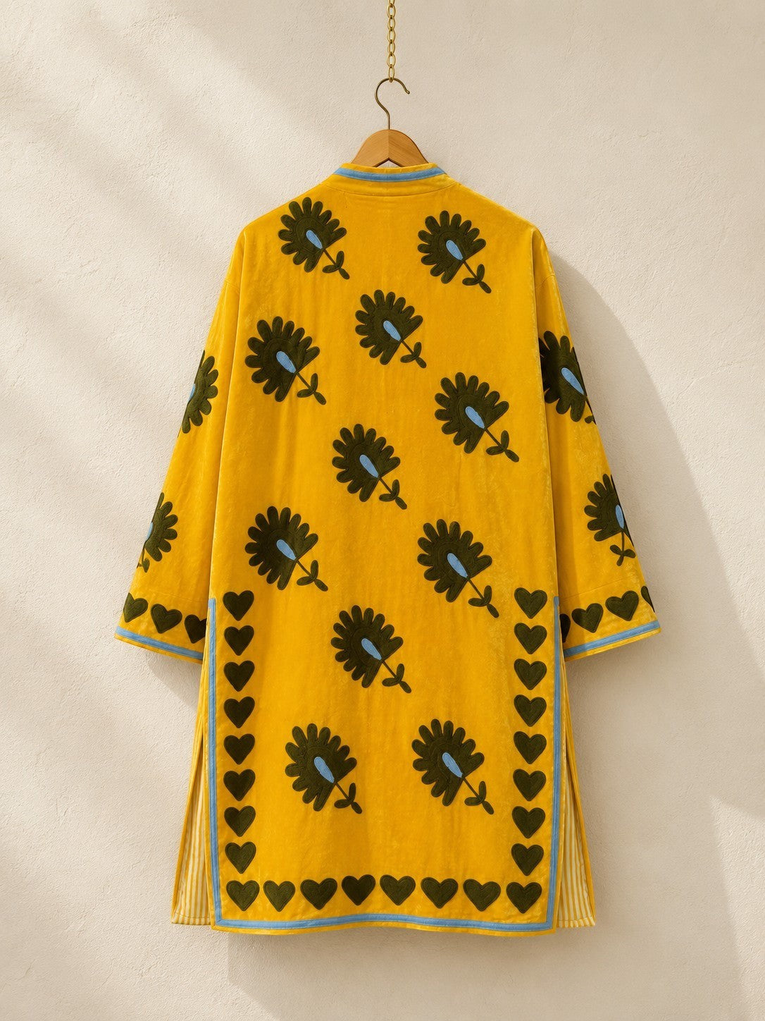 The House of Saffron long saffron velvet jacket featuring dark floral embroidery and a hand-stitched heart border.