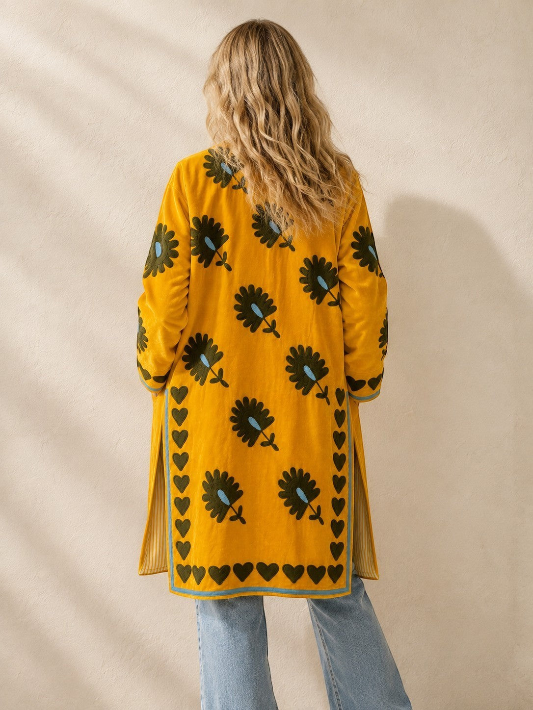 The House of Saffron long saffron velvet jacket with black floral embroidery and a heart-stitched border, back view.