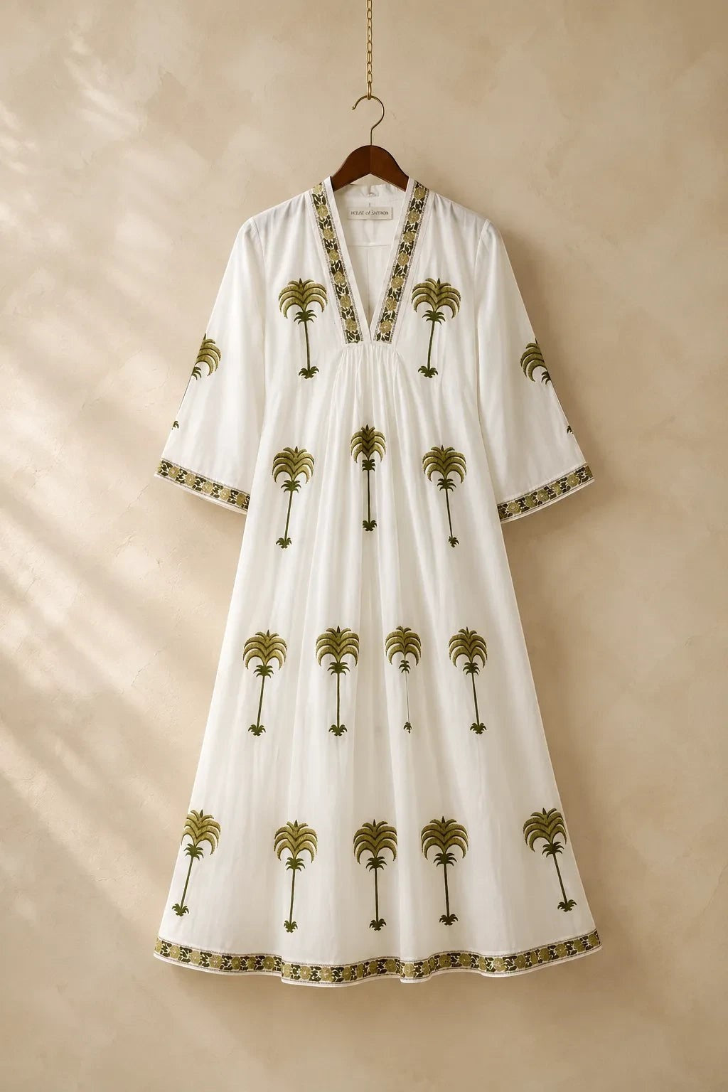 The House of Saffron white midi dress with olive green embroidered palm tree motifs, V-neckline, and patterned trim.